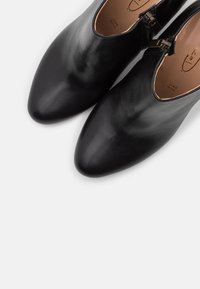 Sorte ankelstøvler i læder med spids tå og sidelukning med lynlås. Glat tekstur og minimalistisk design, med en diskret logo indeni.