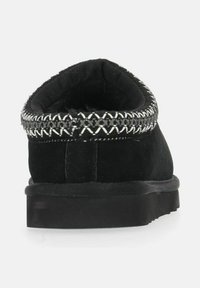 Sorte ruskinds slippers med en afrundet bagside, der har en dekorativ sølvtrådsbroderi rundt om kraven og en flad gummisål.