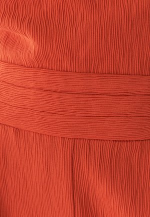 Vestido texturizado en un tono naranja oxidado, con un diseño acanalado y una cinturilla ancha y suave. La tela parece suave con un ligero estiramiento.