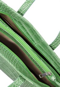 Borsa in pelle verde con stampa a coccodrillo, dotata di doppie zip, manici piatti e una texture liscia. L'interno mostrato è di colore marrone chiaro.
