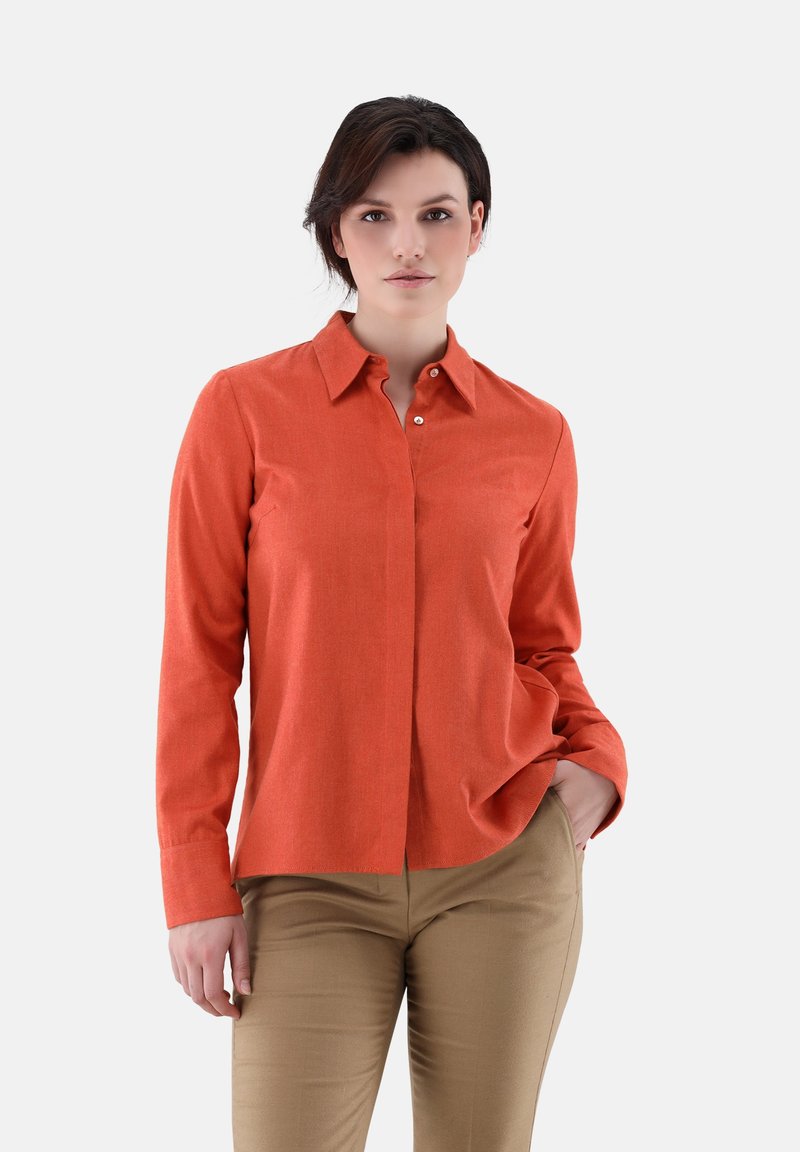 Orange long-sleeve button-up shirt with a collar and smooth texture, paired with beige pants. Features a front pocket and classic fit.