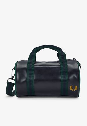Petit sac cylindrique bleu marine avec poignées rayées vertes, bandoulière et logo couronne de laurier jaune à l'avant.