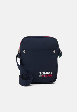 Navyblauwe Tommy Jeans crossbodytas met verstelbare band, voorvak met twee zilveren drukkers en logo in wit en rood aan de voorkant.