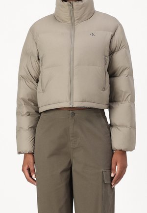 Veste doudoune beige coupée avec col haut, fermeture éclair et poches latérales ; présente une texture lisse et des poignets élastiqués.