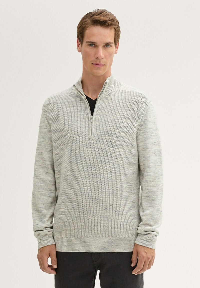 Helles graues Zip-Pullover aus strukturiertem Strickstoff, mit einem hohen Kragen und langen Ärmeln. Subtile Farbvariationen mit gerippten Bündchen.