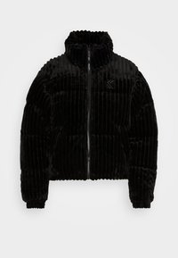 Giacca puffer nera in velluto con colletto alto, texture a costine e cerniera frontale. Presenta un piccolo logo sull'area sinistra del petto.