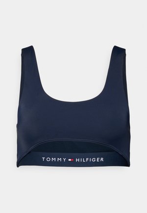 Tumši zils īss topiņš no gludas auduma, ar platu elastīgu jostu, uz kuras attēlots "TOMMY HILFIGER" logotips, bez stīpiņām.