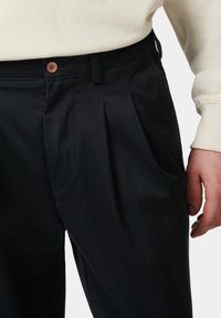Marineblauwe geplooide broek gemaakt van een gestructureerde stof, met een knoopsluiting en zijzakken, met een casual pasvorm en een gladde afwerking.