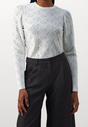 Lichtgrijs long-sleeve shirt met een textuurpatroon en kleine uitsparingen, gecombineerd met donkergrijze hoge taillebroek. Zacht materiaal.