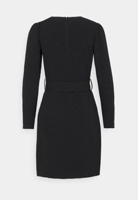 Robe noire à manches longues avec une taille cintrée et une fermeture éclair au dos. Tissu lisse, silhouette ajustée et design minimaliste.