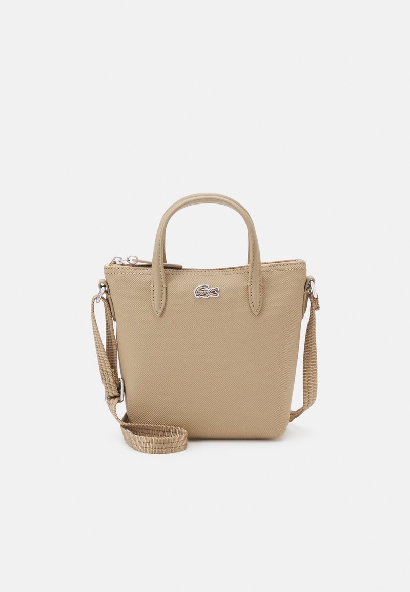 Borsa a mano sintetica beige con due manici corti, una tracolla rimovibile, chiusura con zip superiore e un piccolo logo sul frontale.