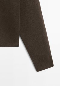 Lång ärm på en mörkbrun stickad tröja med ribbstickad mudd på vit bakgrund.