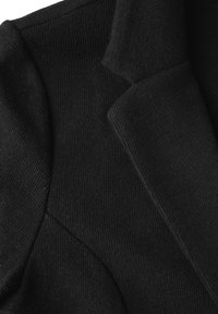 Zwarte gebreide blazer met een gestructureerd ontwerp, ribbeltextuur en scherpe revers, met een close-up weergave die de details van de stof benadrukt.