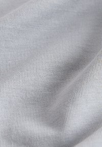 Close-up of light gray knitted fabric showing fine texture and subtle folds.