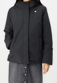 Černá zateplená bunda se zipem, kapucí a logem na levé hrudi; hladký materiál a mírně volný střih; boční kapsy.