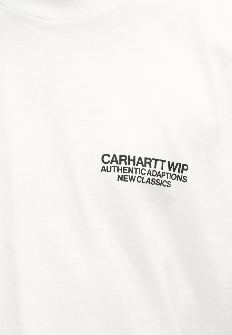 Tessuto bianco con testo nero "CARHARTT WIP AUTHENTIC ADAPTATIONS NEW CLASSICS" stampato sulla parte superiore del petto.