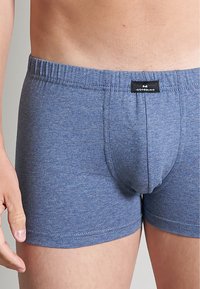 Blauwe katoenen boxershorts met een elastische tailleband en een voorzak voor ondersteuning. De stof heeft een subtiele gemêleerde textuur. Zwarte label zichtbaar.