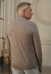 Grey knit sweater with a ribbed hem and cuffs, featuring a smooth texture and a fitted silhouette, shown from the back.