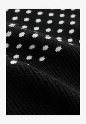 Tissu tricoté noir avec des pois blancs, présentant un motif côtelé texturé. Le matériau semble doux et extensible.