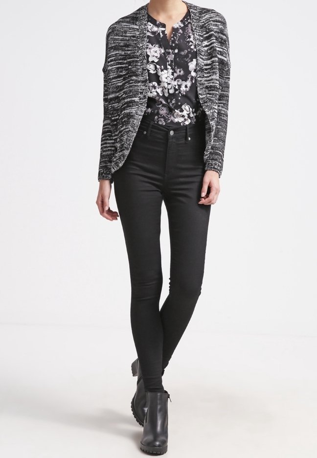 Black and white patterned cardigan over a floral shirt, paired with black skinny jeans and black ankle boots. Smooth texture and fitted design.