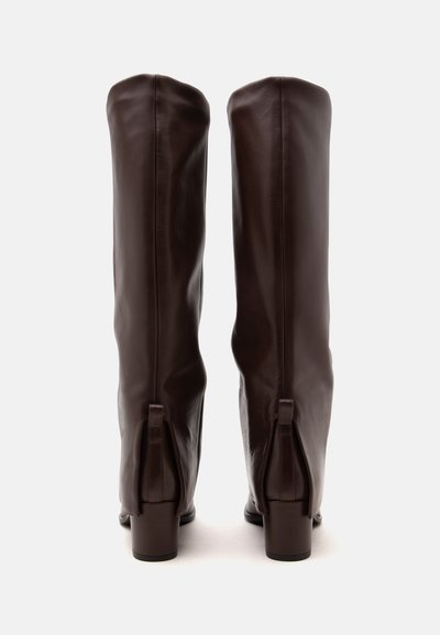 Paire de bottes hautes en cuir marron foncé avec talons blocs, vues de dos sur un fond blanc uni.