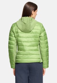 Zielona kurtka puchowa o gładkiej, błyszczącej fakturze i poziomym pikowanym wzorze. Posiada kaptur wykonany z miękkiego, pasującego zielonego materiału.