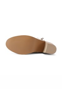 Suola di scarpa beige con una finitura in gomma testurizzata, dotata di un leggero tacco e scanalature decorative per la trazione. Superficie piatta con una forma arrotondata.