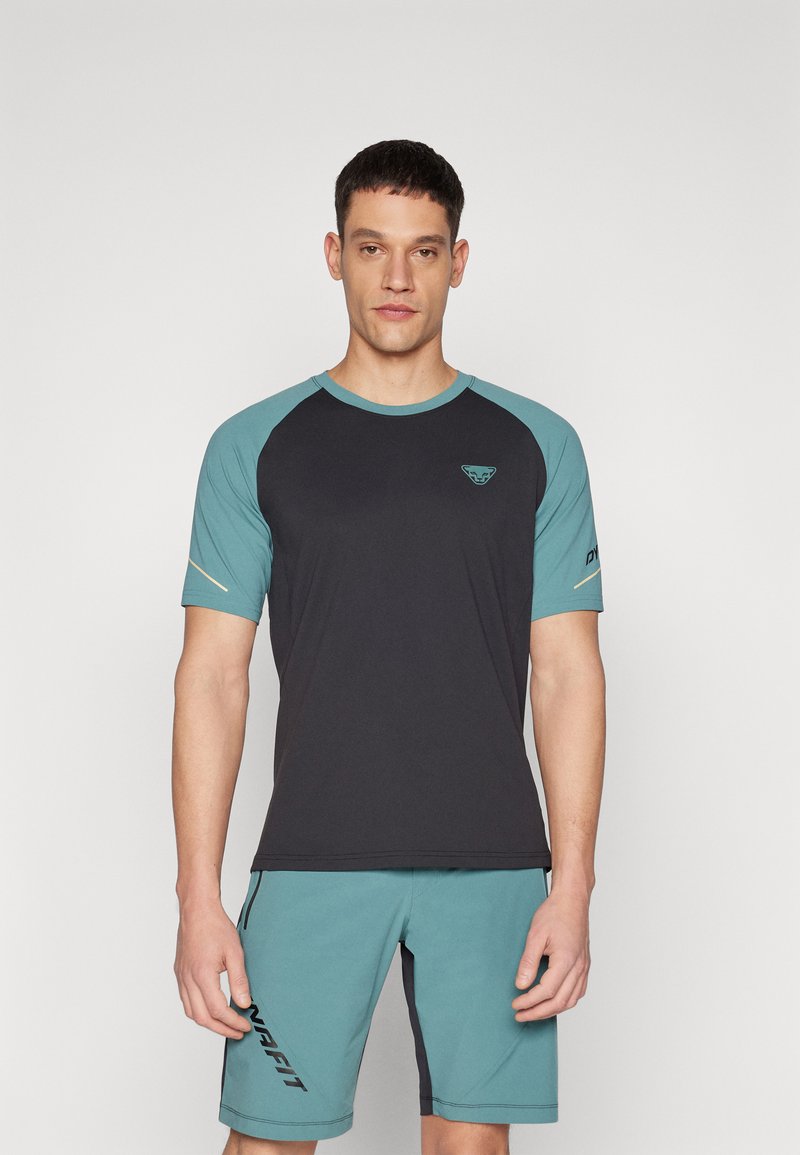 Pánský sportovní outfit skládající se z černého trička s aquamarínovými rukávy a logem, doplněný aquamarínovými šortkami s černou grafiku značky. Hladký materiál.