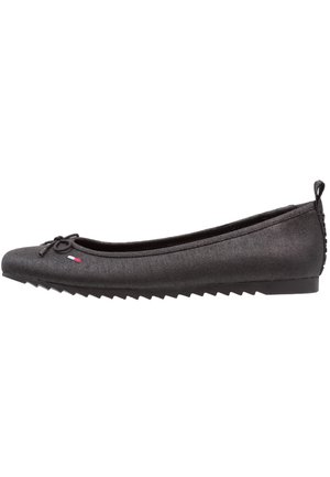 Schwarze Ballettschuhe aus Stoff mit runder Spitze, Schleifenakzent und strukturierter Oberfläche. Sie verfügen über eine Zickzack-Gummisohle mit einem kleinen Absatz.