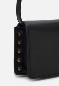 Mustan nahkalaukun suorakaiteen muotoinen, jossa on kultaisia niittejä yhdellä sivulla ja tyylikäs, sileä pinta.