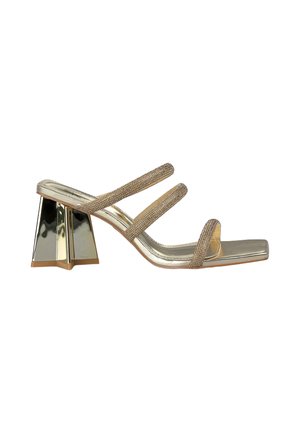 Sandalo con tacco a strappo caratterizzato da una finitura dorata metallizzata, cinturini riccamente decorati e un tacco a blocco riflettente di forma unica.