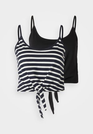 Ριγέ αμάνικο μπλουζάκι με λεπτομέρεια κόμπου, άνετο μπεζ φαρδύ παντελόνι, μαύρες σανδάλες και κρεμ τσάντα. Το μοντέλο φορά μαύρα γυαλιά ηλίου.