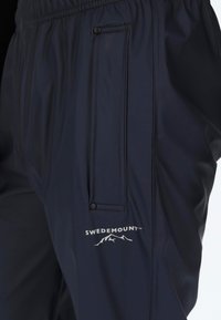 Wasserfeste schwarze Hose mit elastischem Bund, Reißverschluss-Tasche und "SWEDEMOUNT"-Logo. Glattes, strapazierfähiges Material mit einem eleganten Design.