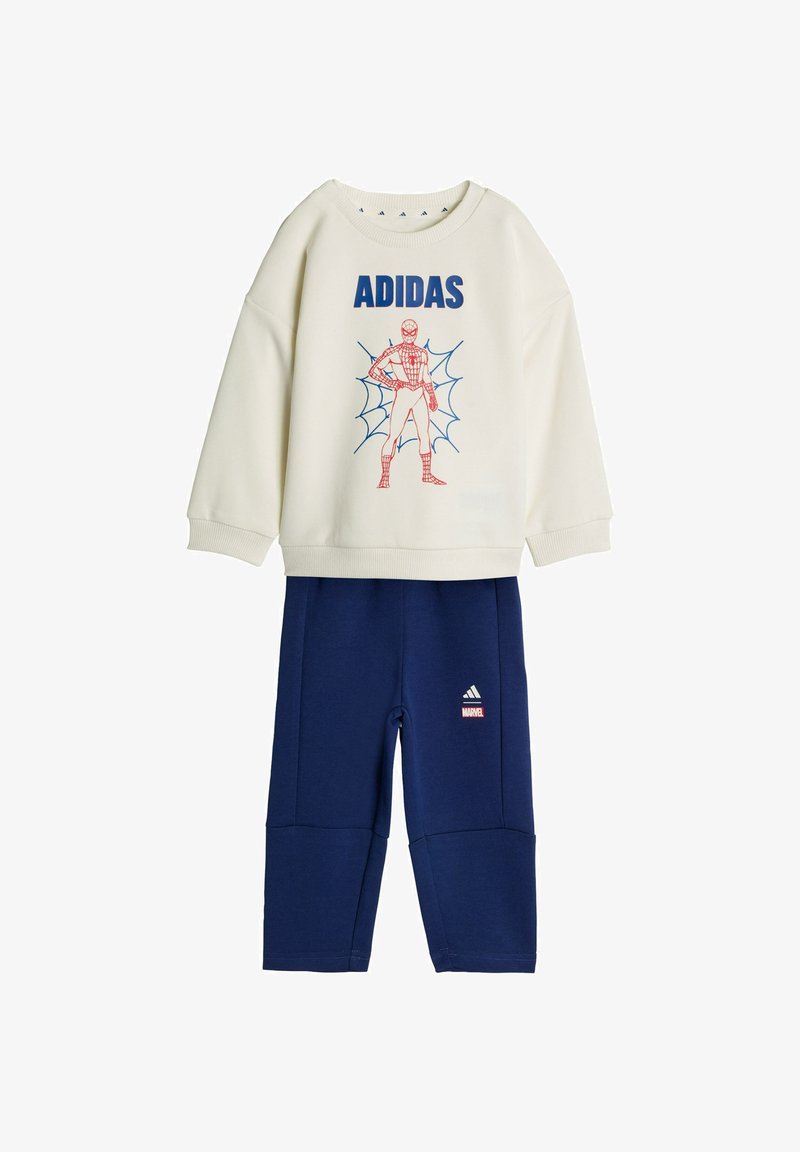Krémová mikina s modrým nápisom „ADIDAS“ a červenou grafikou Spider-Mana, kombinovaná s tmavomodrými nohavicami s logami Adidas a Marvel.