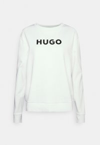 Bílá mikina s dlouhými rukávy, kulatým výstřihem a černým logem "HUGO" na hrudi. Vyrobena z měkké bavlny.
