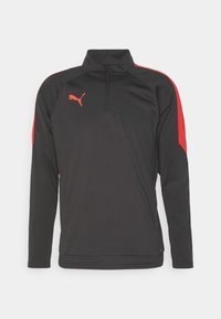 Schwarzer Pullover mit langen Ärmeln und hohem Kragen, roten Akzenten an den Schultern und einem kleinen roten Logo auf der linken Brust. Glatte Stoffstruktur.