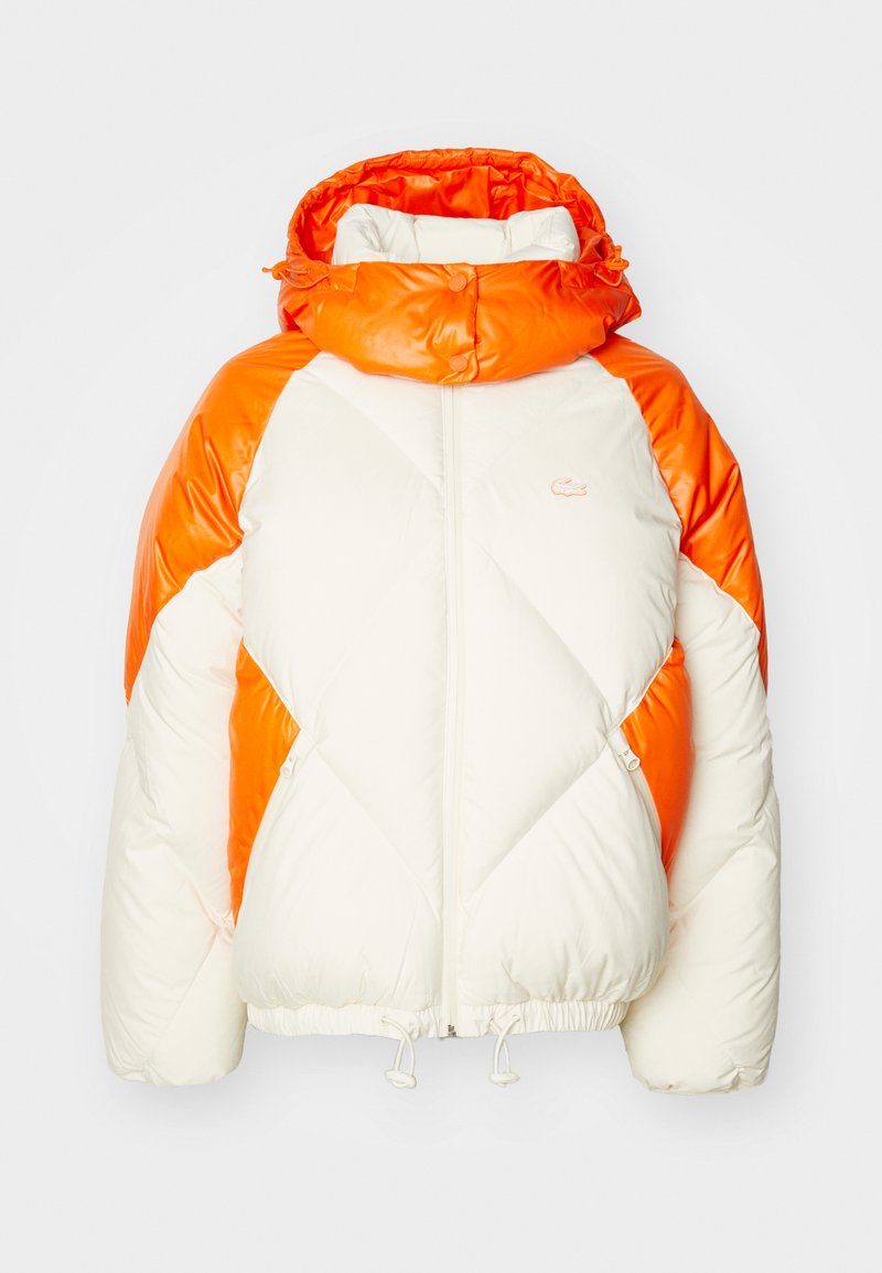 Giacca imbottita con finitura lucida, caratterizzata da un corpo bianco e accenti arancioni vivaci. Include un collo alto e un orlo elasticizzato con cordini.