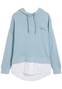 Felpa blu chiaro in tessuto texturizzato, con cappuccio regolabile e la scritta "STORIES OF NEW YORK" ricamata in viola. Indossata sopra una maglietta bianca.