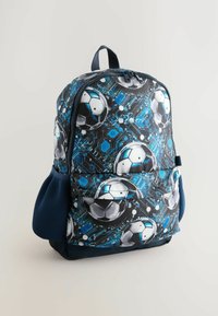 Mochila negra y azul con estampado de balón de fútbol y diseño abstracto de circuitos azules. Posee bolsillos laterales de malla y un tejido duradero.