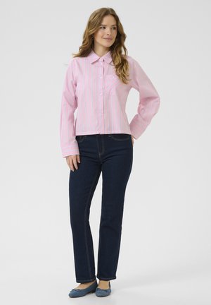 Pink and white striped button-up shirt with a collar, featuring a chest pocket. Worn with dark blue straight-leg jeans and blue flats.