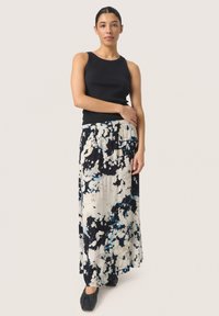 Mustrend mustriga tank top musta ribiga, mis on kombineeritud voolava mustriga maxi seelikuga, millel on sinised ja mustad laigud kreemikal taustal. Mustad jalanõud.