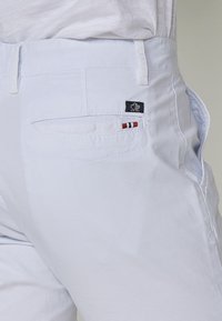Svijetloplave pamučne hlače s stražnjim džepom na kojem se nalazi mala oznaka s logotipom i crvenim, bijelim i plavim prugama. Glatka tekstura, dizajn ravnih nogavica.