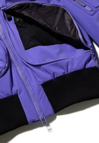Lila bomber dzseki fekete bordázott mandzsettákkal, cipzáras záródással és belső hálós zsebbel. Sima textúrájú, tartós anyagból.