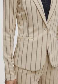 Beiger gestreifter Blazer aus glattem Stoff mit schmalen braunen vertikalen Streifen, einer einzelnen Knopfverschluss und seitlichen Taschen.