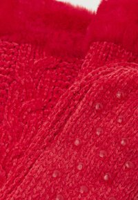 Røde strikede hjemmesko med en blød top, struktureret væv og gummidutter på sålen for bedre greb. Det bløde, fuzzy materiale øger komforten.