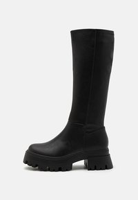 Black knee-high boots made of faux leather, featuring a chunky rubber sole with deep grooves, smooth surface, and minimal stitching details.