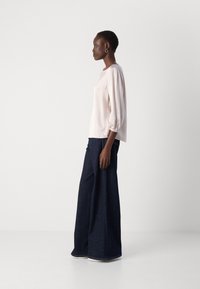 Light pink satin blouse with three-quarter puff sleeves, paired with dark denim wide-leg trousers. Smooth texture and simple design.