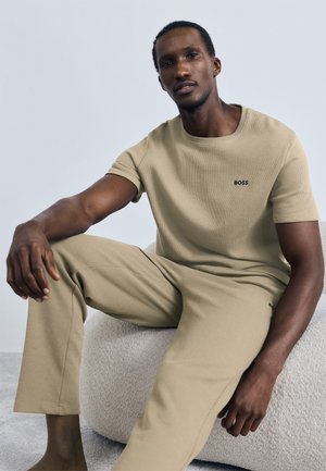 T-shirt texturada bege e calças a condizer, ambos com corte descontraído. A t-shirt apresenta um pequeno logótipo preto "BOSS" no peito.