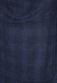 Marinblå ulltyg med ett subtilt rutmönster, med mjuk textur och en fickdetalj.