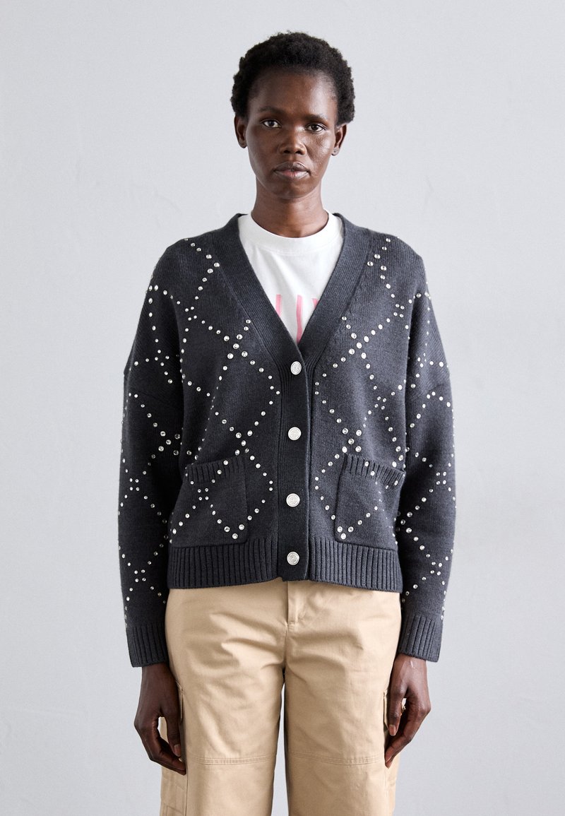 Tumšs pelēks džemperis ar pērļu rotājumiem, V veida kakla izgriezumu, ribotām piedurknēm un apakšmalu, ar pogu aizdari un divām priekšējām kabatām.